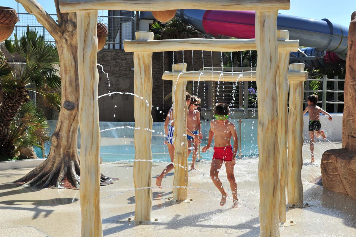 Photo professionnelle d'enfants jouant avec des jets d'eau au camping par Koro Marketing